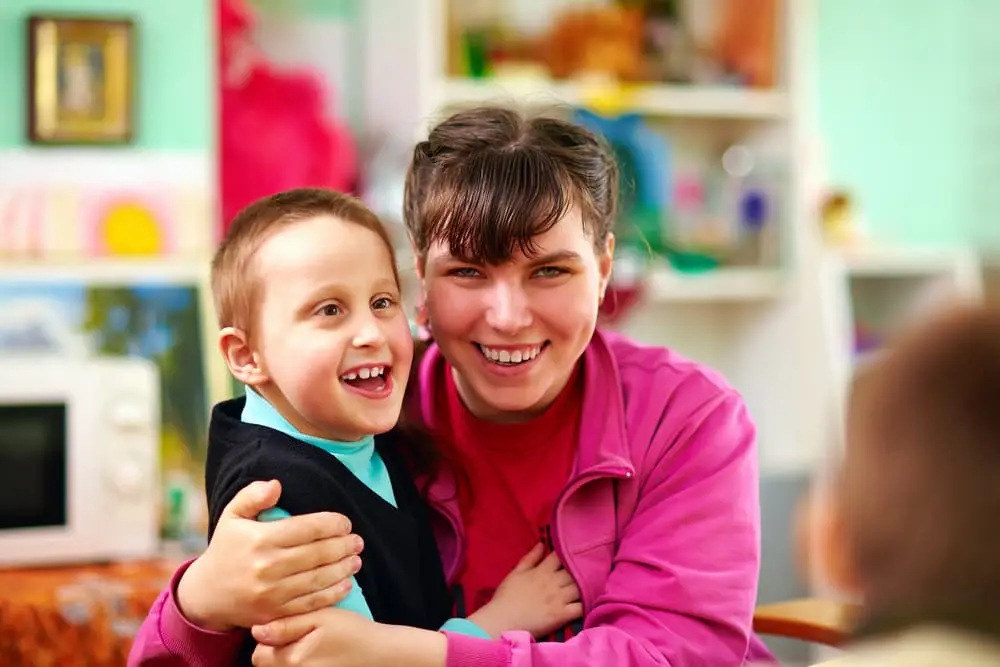 Happy Child Hugging Teacher — Supported Independent Living in Bundaberg, QLD