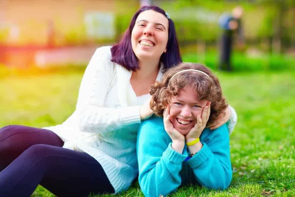 Two Girls Laying In Grass — Supported Independent Living in Bundaberg, QLD